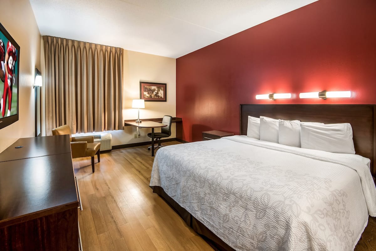 Habitación de hotel con una cama grande, un escritorio, una silla y un televisor.