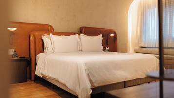 Una habitación de hotel con una cama grande, una mesita de noche, una lámpara y una ventana con cortinas.