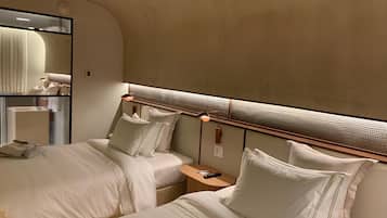 A hotel room with two beds, a large mirror, and a modern headboard with built-in lighting.