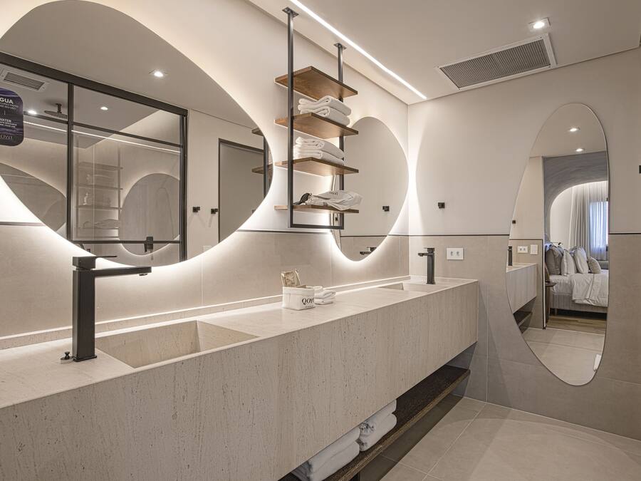 A modern bathroom with a large mirror, dual sinks, and a towel rack.