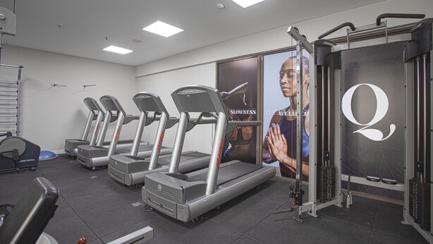 A gym with treadmills, weight machines, and a large mirror. - QOYA Hotel Curitiba, Curio Collection by Hilton (Curitiba)