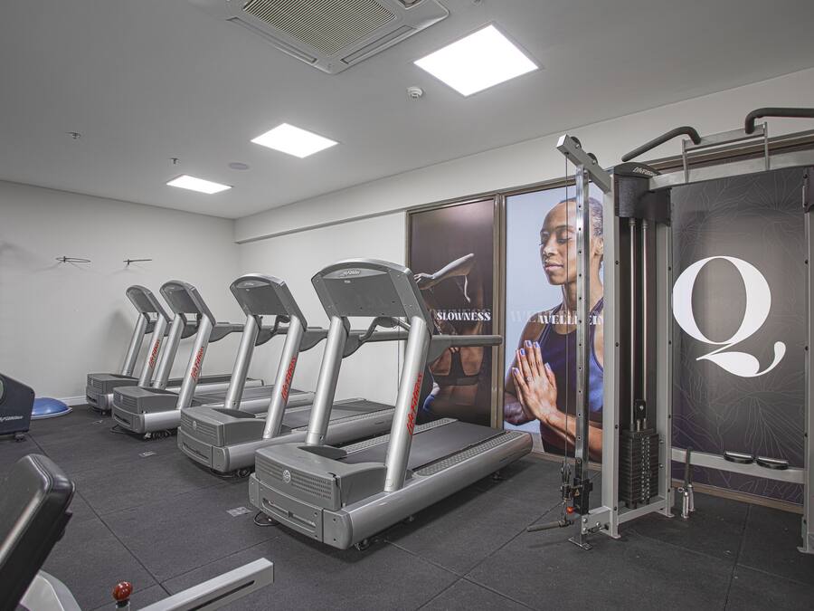 Une salle de sport équipée de tapis de course, d’appareils de musculation et d’un grand miroir.