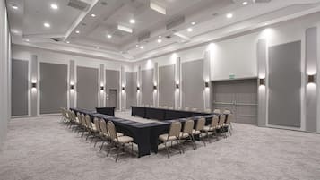 Una sala de conferencias con una larga mesa, sillas y suelo alfombrado.