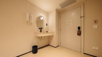 A hotel bathroom with a sink, mirror, towel rack, and a door with a lock.