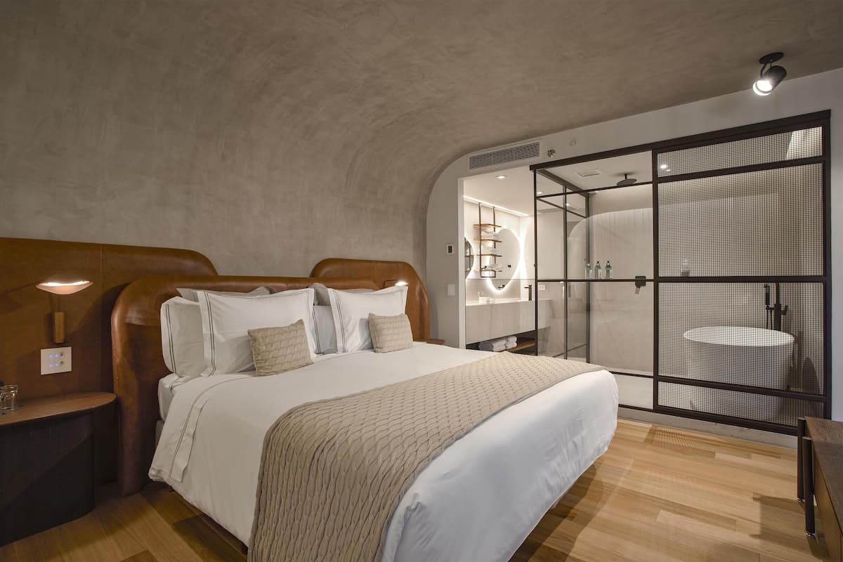 Ein Schlafzimmer mit einem großen Bett, Nachttischen, einem Schrank und einem Badezimmer mit Glasabtrennung.