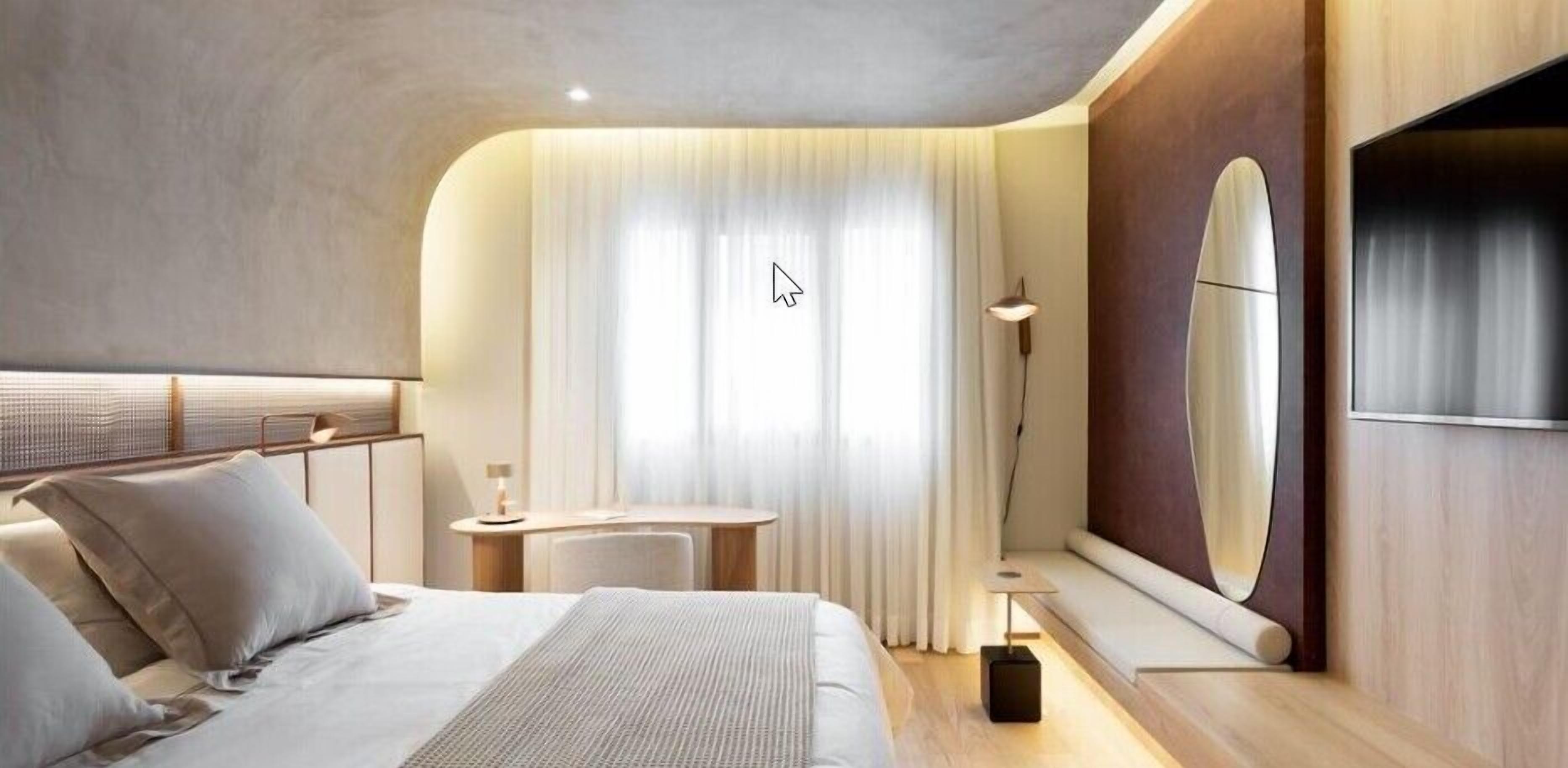 Une chambre d’hôtel moderne équipée d’un lit, d’un bureau, d’une chaise, d’une lampe et d’un grand miroir.