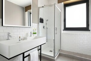 A modern bathroom with a white sink, a glass shower enclosure, and a large mirror.