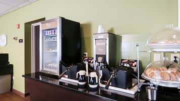 A coffee station with a coffee machine, a waffle maker, and a display case with waffles.