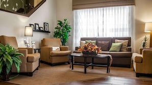 A living room with a sofa, armchairs, a coffee table, and a large window with curtains. - Sleep Inn & Suites (Hagerstown)