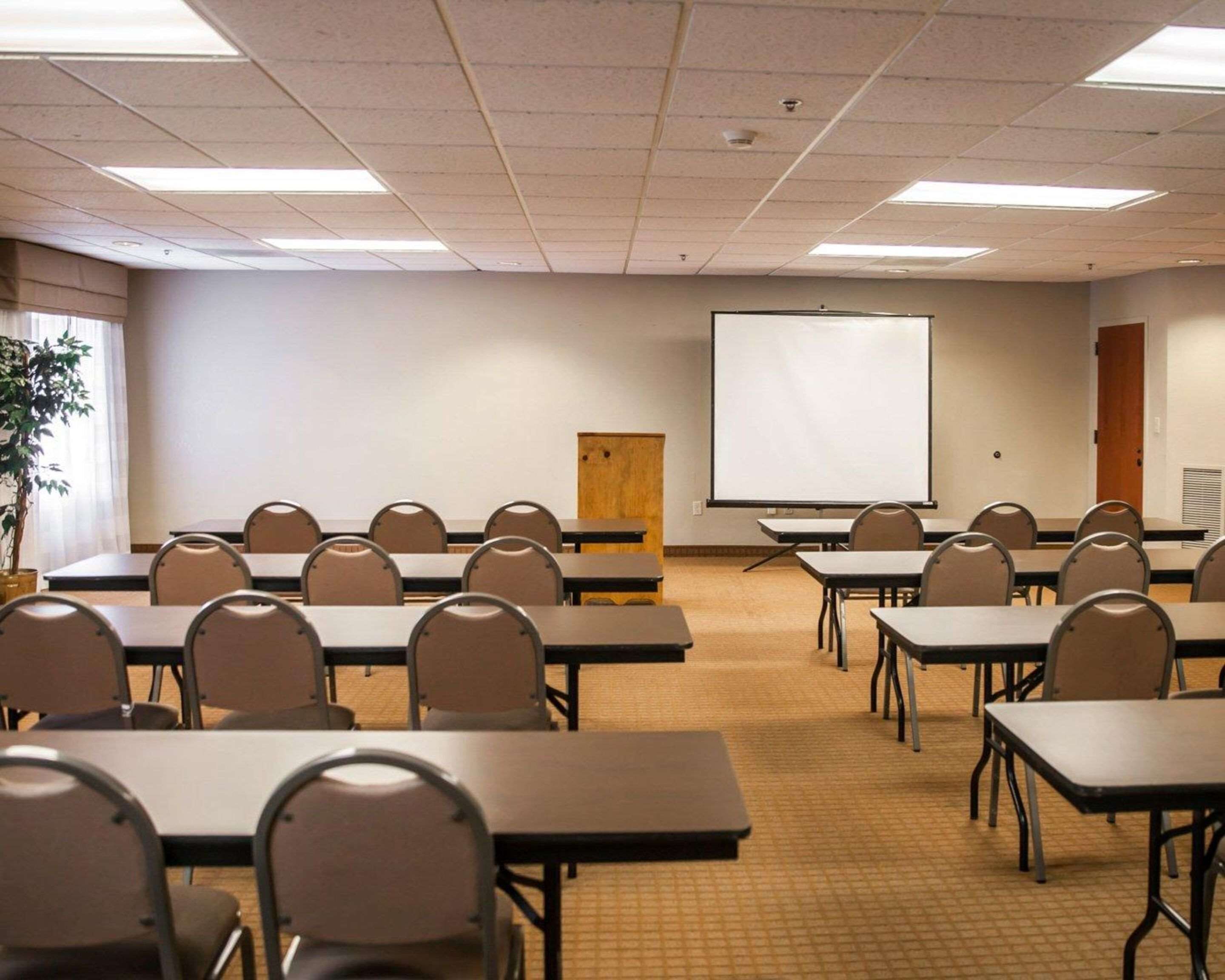 A conference room with tables and chairs, a projector screen, and a door.