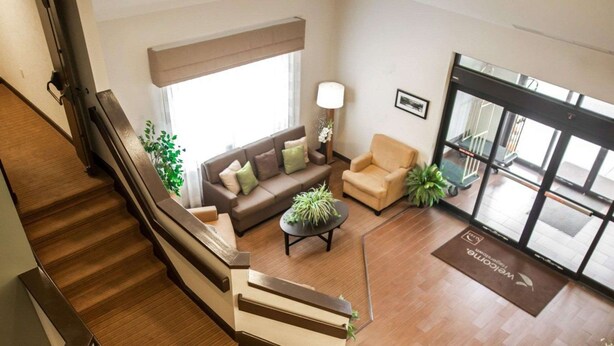 A modern hotel lobby with a staircase, a sofa set, a coffee table, and a reception desk. - Sleep Inn & Suites (Hagerstown)