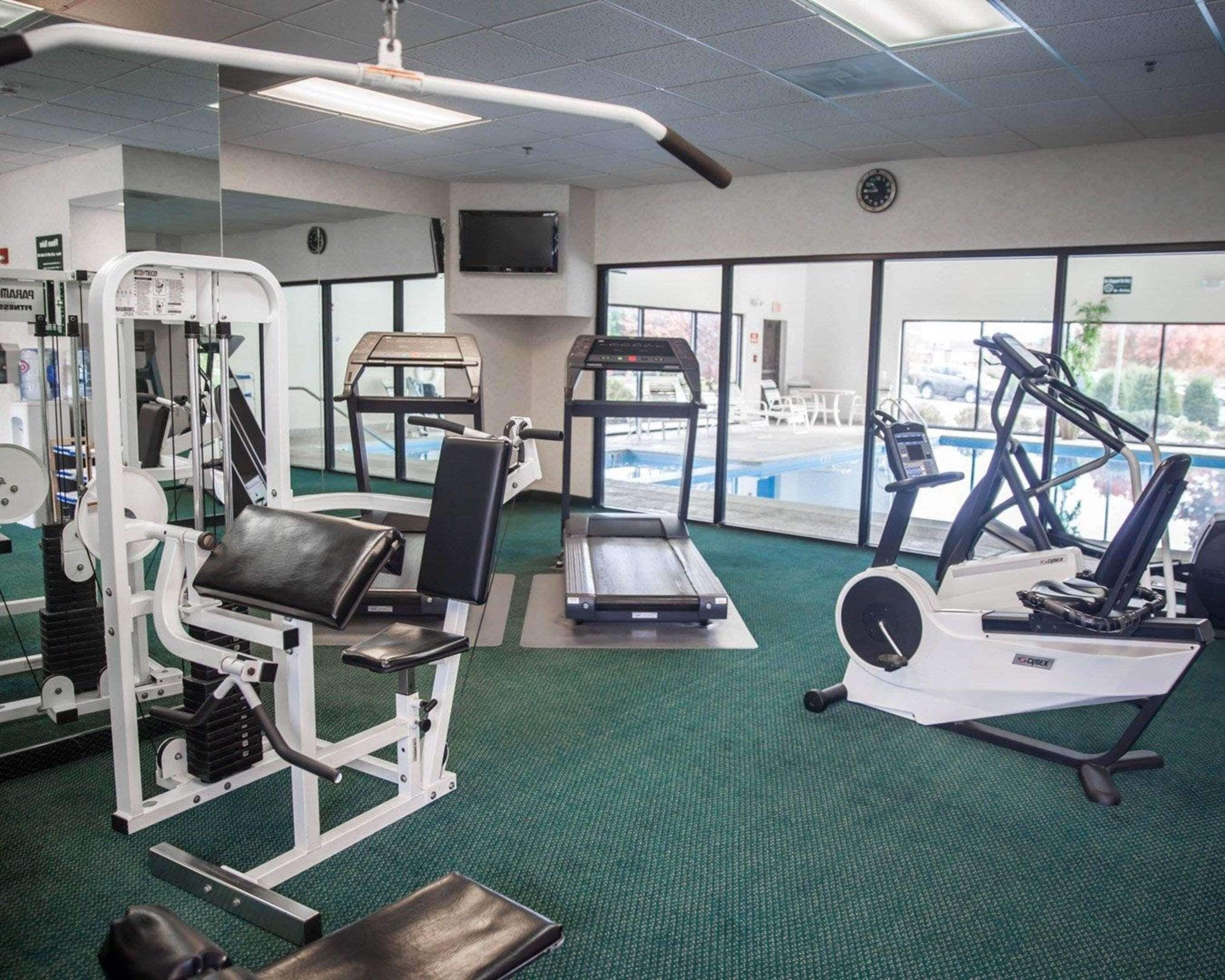 A gym with cardio machines, weightlifting equipment, and a pool area.