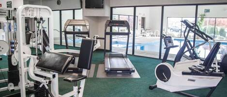 A gym with cardio machines, weightlifting equipment, and a pool area.