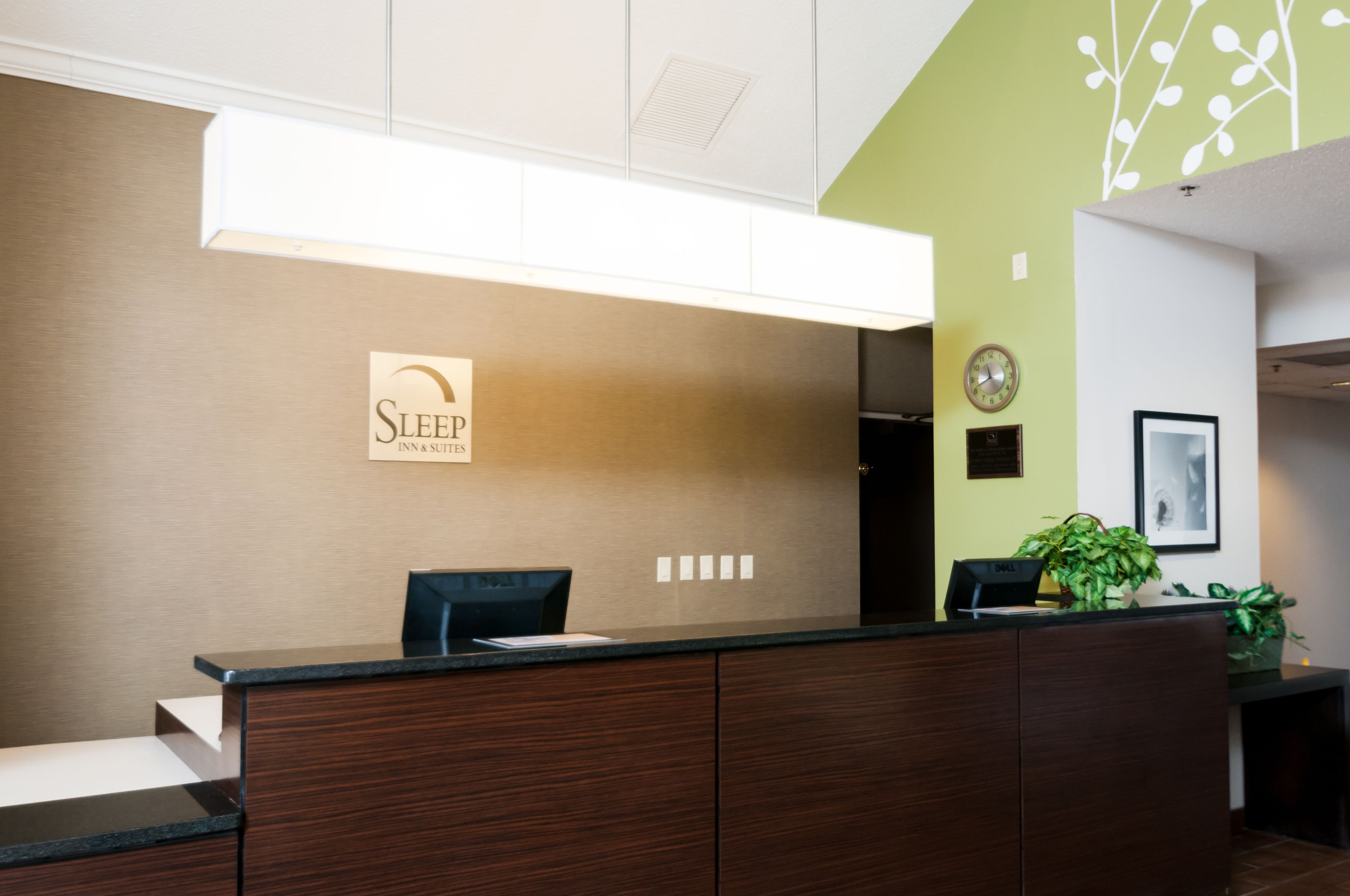 Una recepción con un cartel que dice 'Sleep Inn Suites', un reloj y un cuadro en la pared.