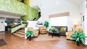 A spacious lobby with a staircase, a sofa set, and potted plants. - Sleep Inn & Suites (Hagerstown)