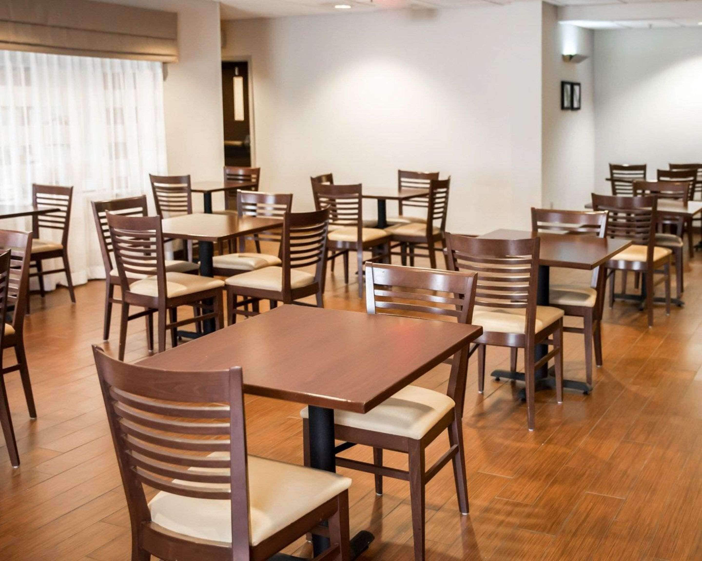 Un vaste espace dédié à la salle à manger, avec de nombreuses tables et chaises en bois, disposées en rangées.