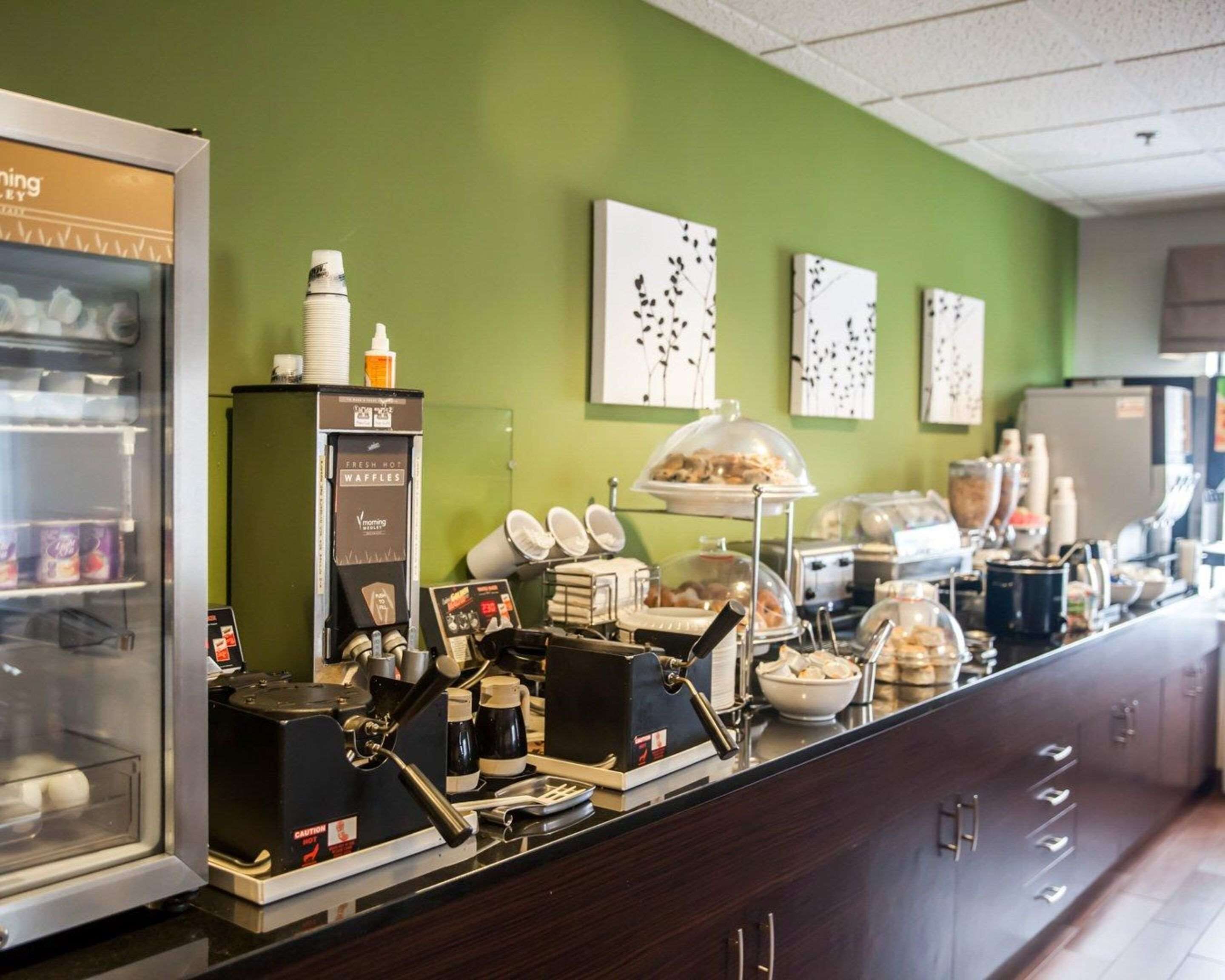 A breakfast bar with a coffee machine, waffle station, and various food containers.