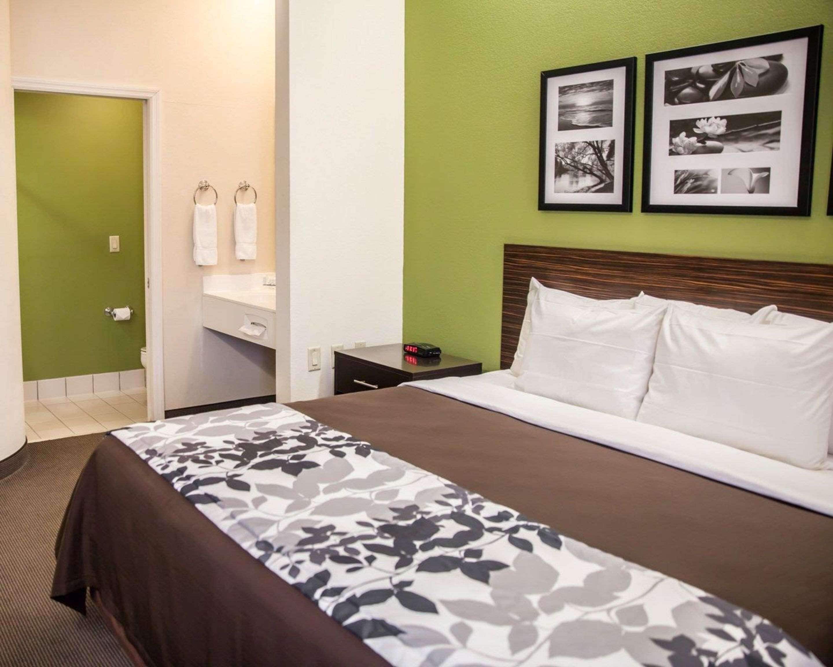 A hotel room with a bed, a nightstand, a mirror, and a green wall.