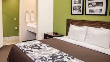A hotel room with a bed, a nightstand, a mirror, and a green wall.