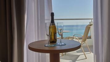 Un tavolo con una bottiglia di vino e due bicchieri su un balcone con vista sul mare.