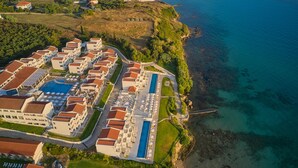 An aerial view of a coastal resort with multiple buildings, a swimming pool, and a pier extending into the sea. - AluaSoul Zakynthos - Adults Only - All Inclusive (Zakynthos)