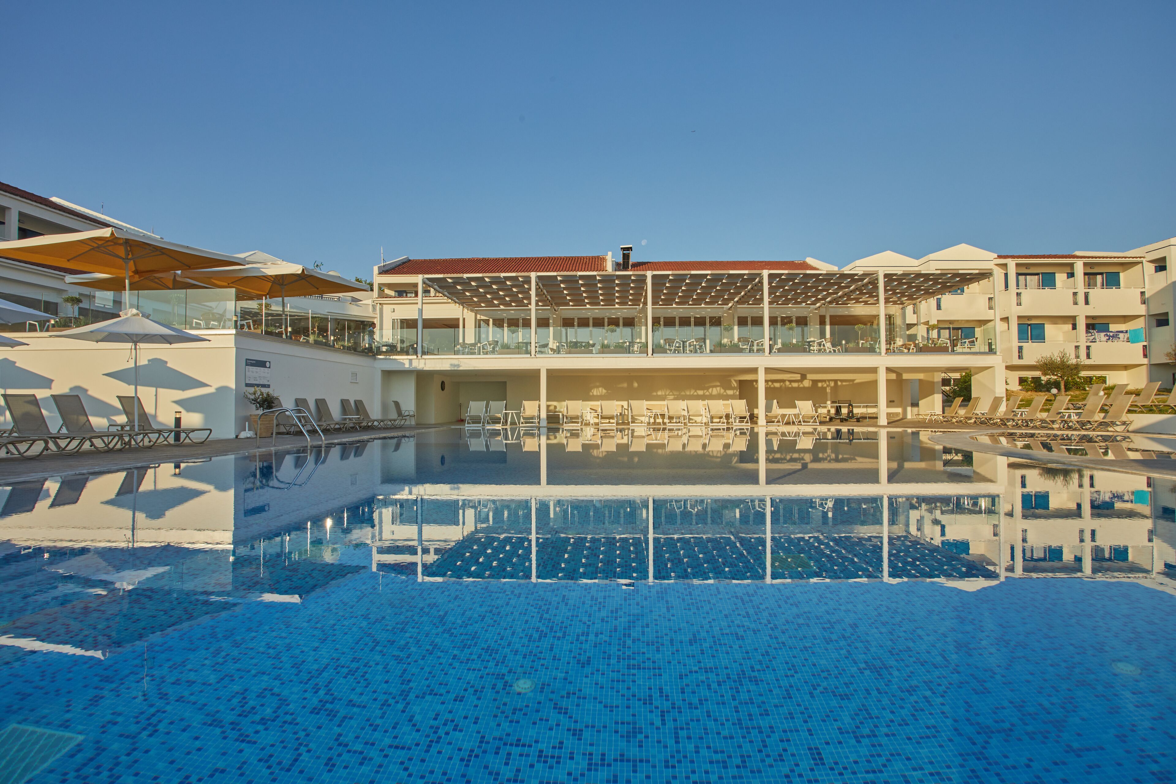 Una piscina con lettini e una zona relax coperta.