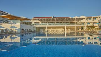 Una piscina con lettini e una zona relax coperta.