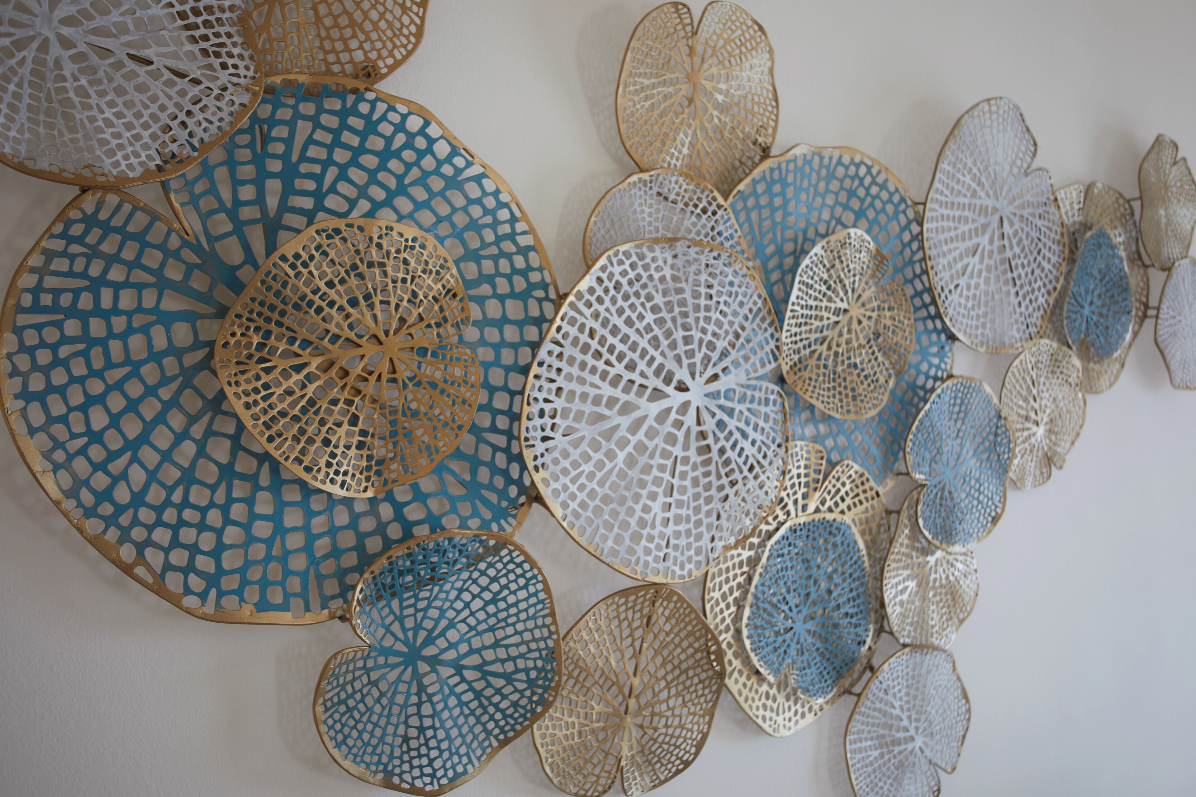 A collection of circular, perforated wall art pieces in various sizes and shades of blue and beige.