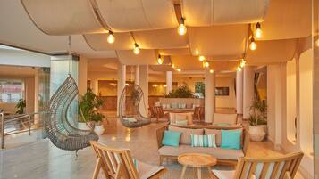 A spacious lobby with a seating area, hanging chairs, and potted plants.
