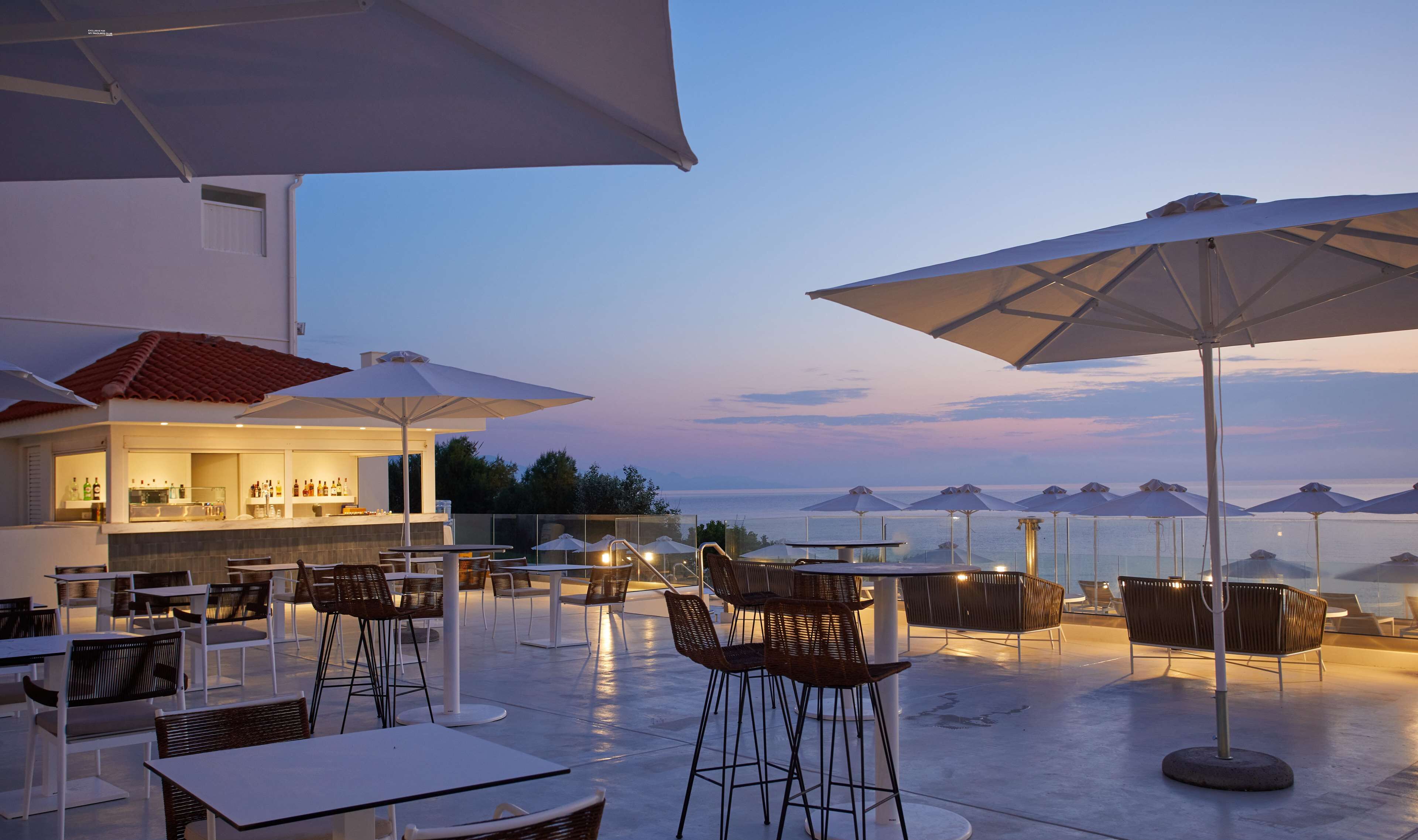 An outdoor seating area with tables and chairs, umbrellas, and a bar.