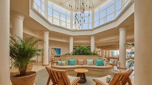 A spacious lobby with a high ceiling, large windows, and a central seating area with sofas and chairs. - AluaSoul Zakynthos - Adults Only - All Inclusive (Zakynthos)