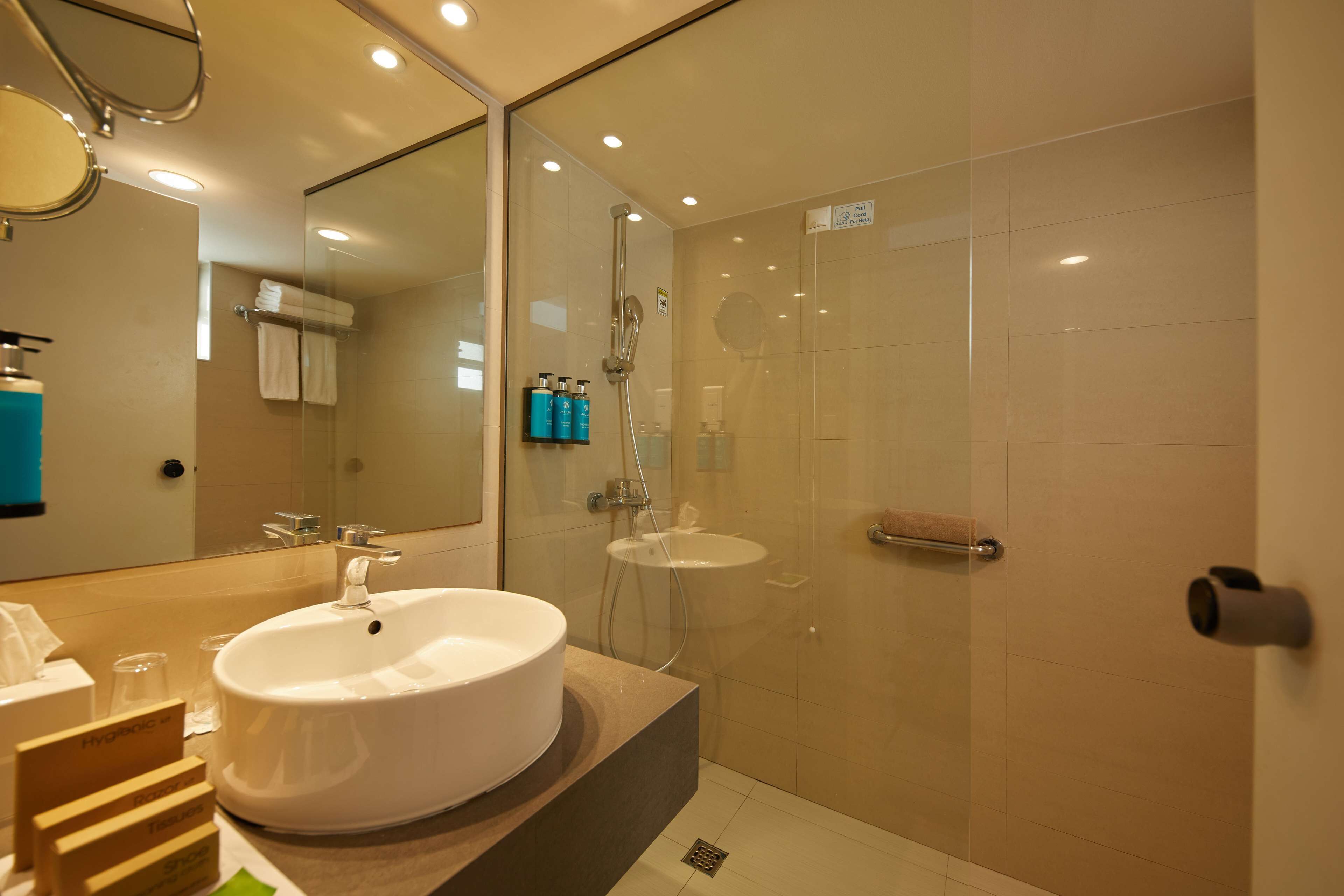 A modern bathroom with a large mirror, a round sink, a glass-enclosed shower, and a towel rack.