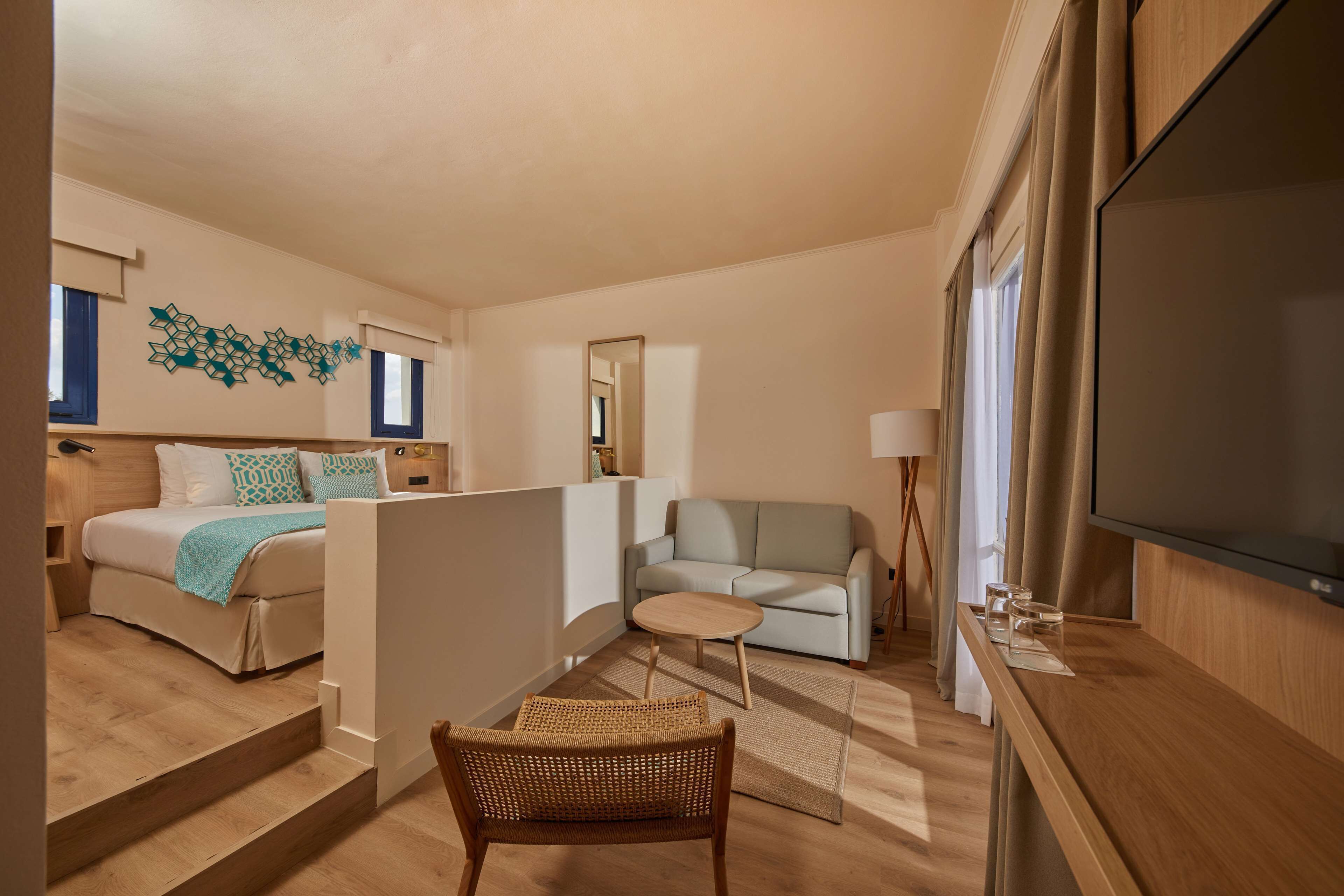 Une chambre d’hôtel moderne équipée d’un lit, d’un canapé, d’une télévision et d’un coin repas.