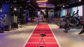 Un gimnasio con pista de correr roja, equipo de halterofilia y máquinas de ejercicio.