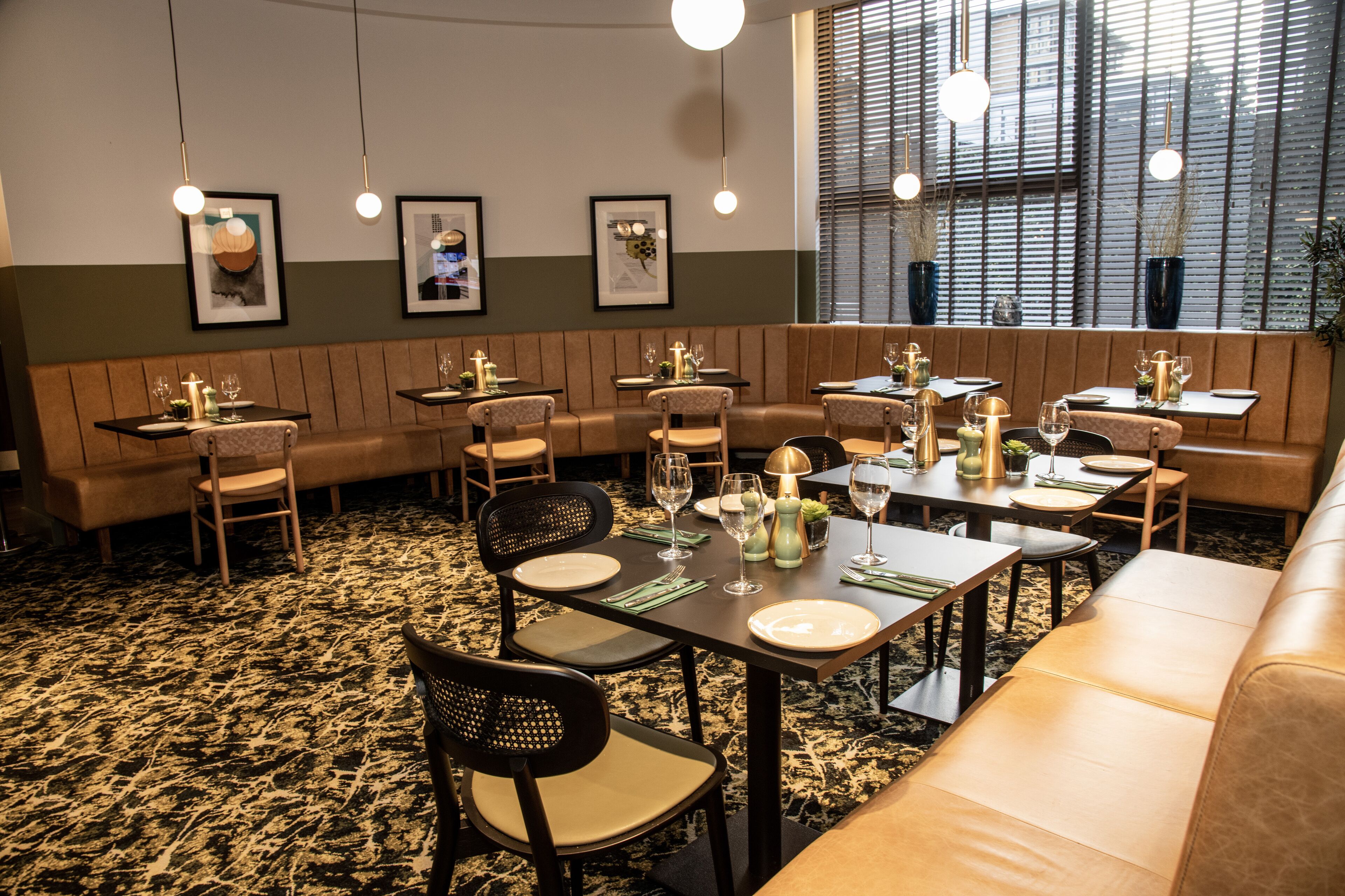 Um restaurante com cabines e mesas, quadros nas paredes e luminárias pendentes.