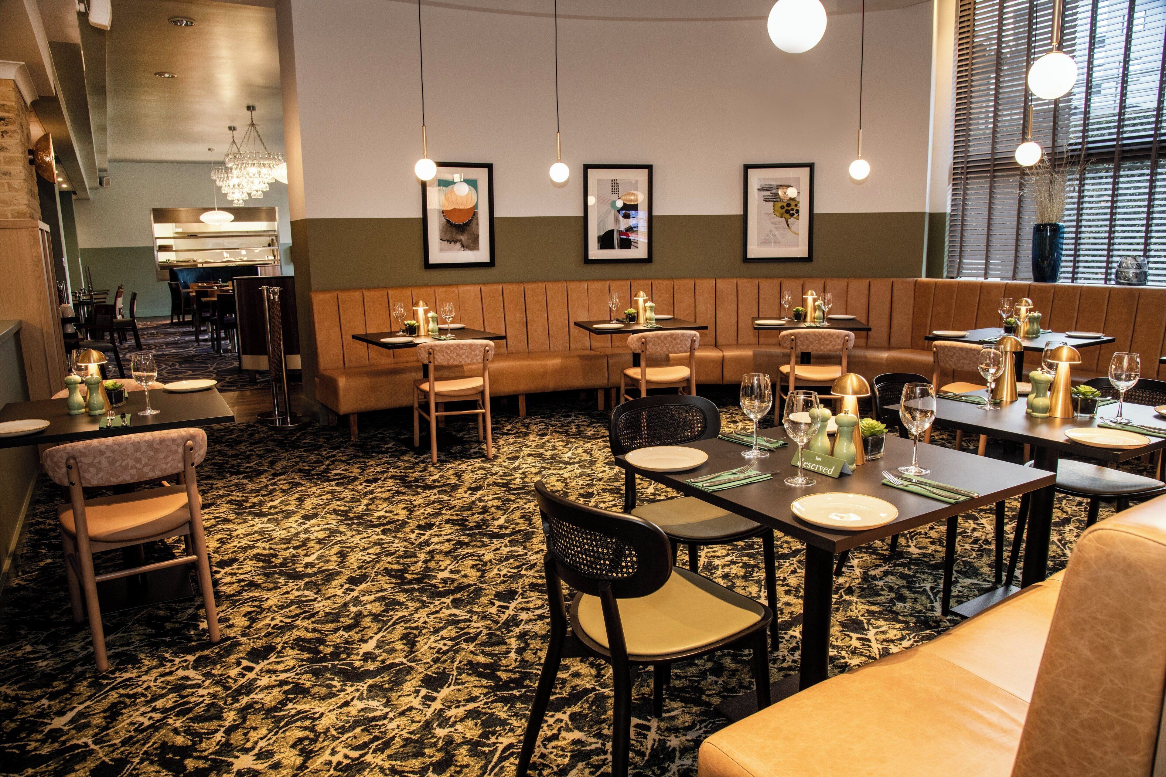 A restaurant with booths and tables, framed artwork on the walls, and a patterned carpet.