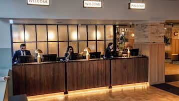 A reception desk with three employees, a 'WELCOME' sign above, and a modern interior design.