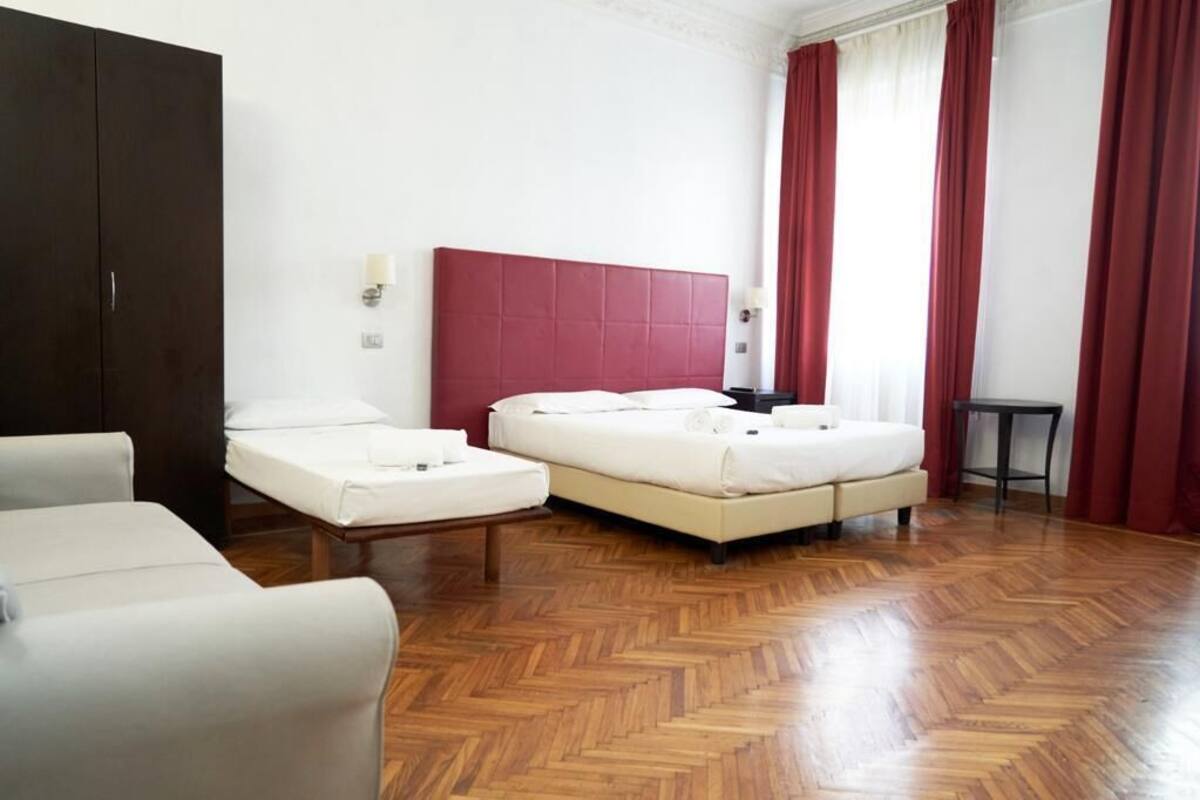 A hotel room with a large bed, a bedside table, a chair, and a wardrobe.
