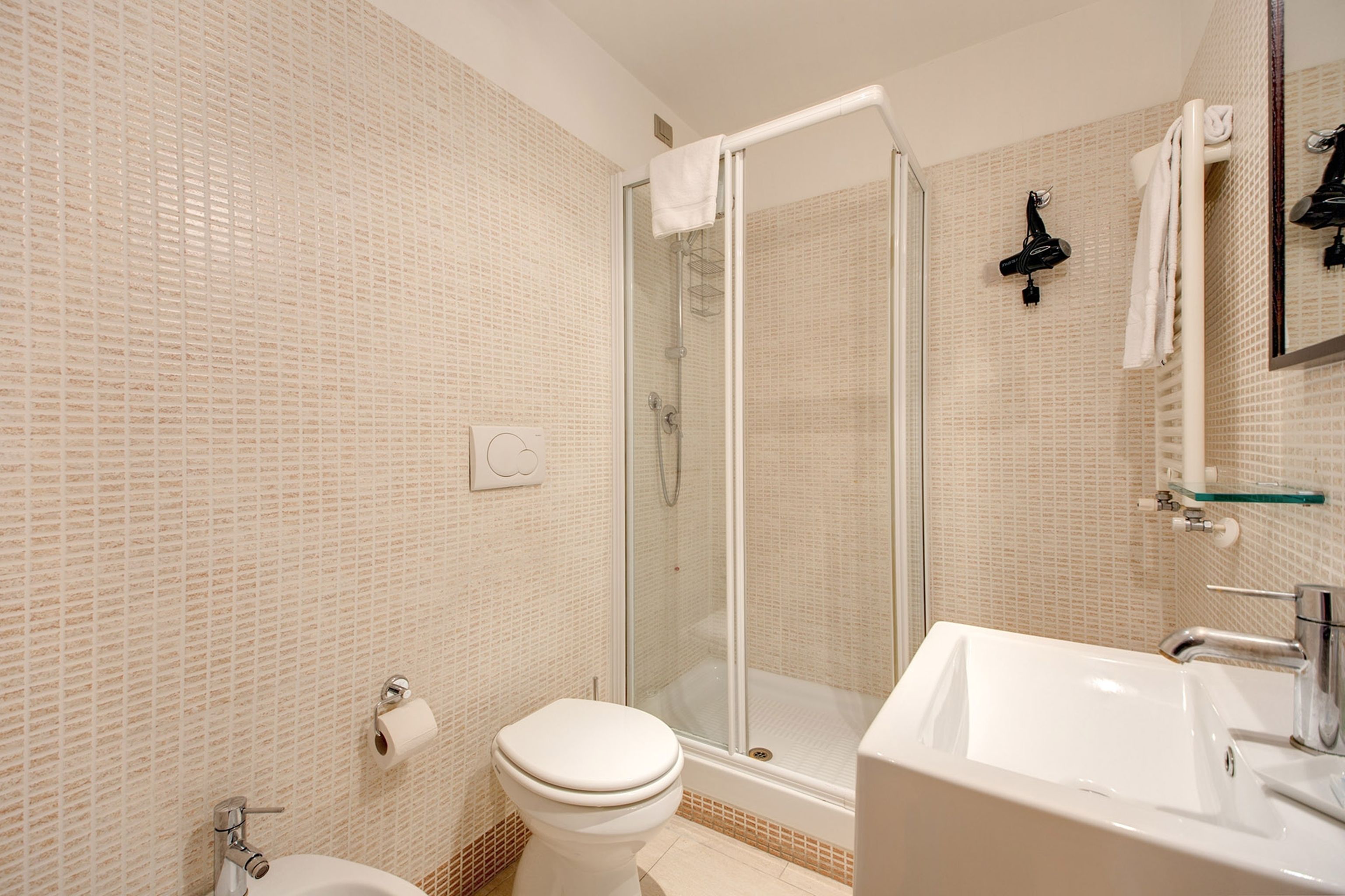 A bathroom with a toilet, shower, and sink.