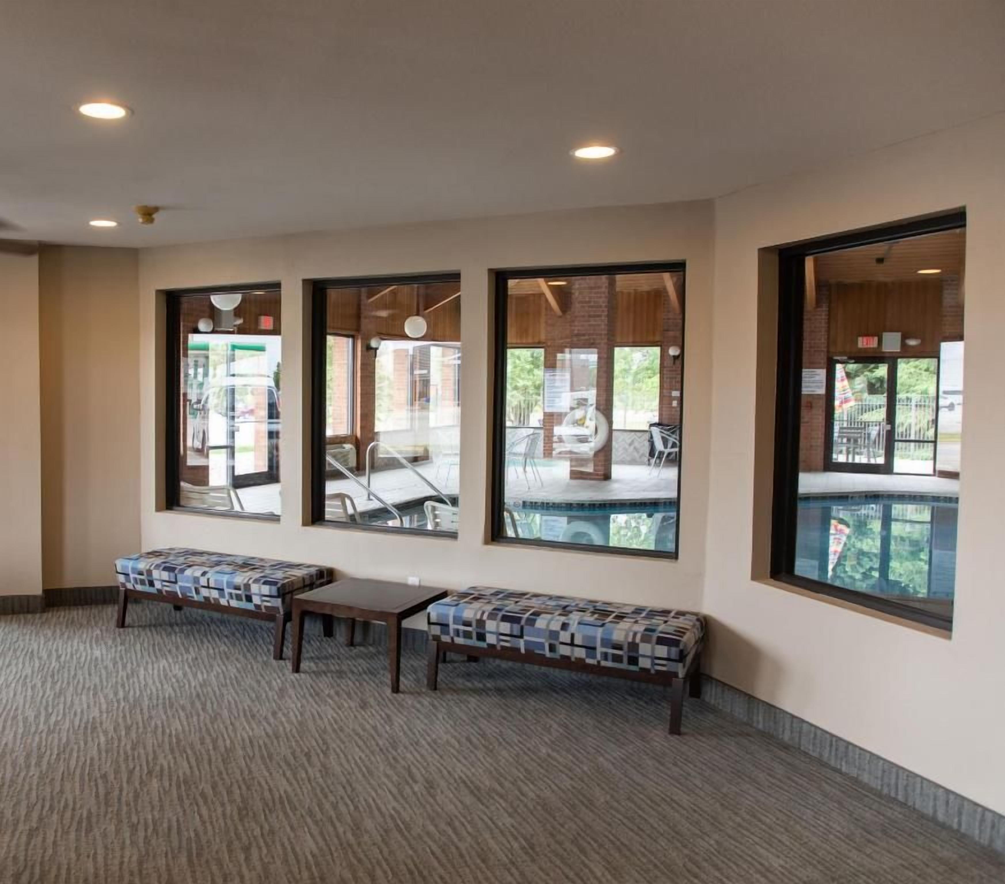 A lobby with large windows, a carpeted floor, and a bench.