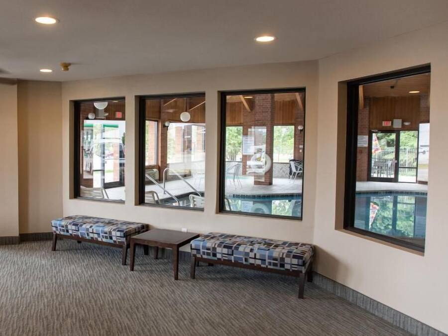 A lobby with large windows, a carpeted floor, and a bench.