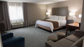 A hotel room with a bed, two bedside tables with lamps, a desk, and two chairs.