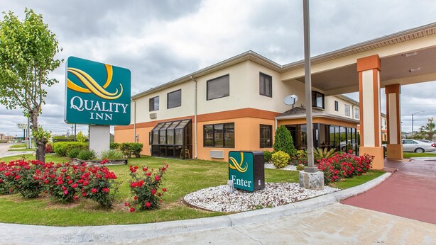 A Quality Inn hotel with a clear entrance, a landscaped garden with red flowers, and a parking area. - Quality Inn Montgomery South (Montgomery)