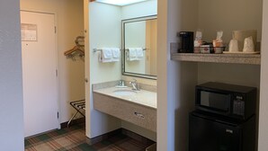A hotel bathroom with a sink, mirror, towel rack, and a microwave. - Quality Inn Montgomery South (Montgomery)