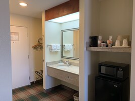Un baño de hotel con lavabo, espejo, perchero para toallas y un microondas.