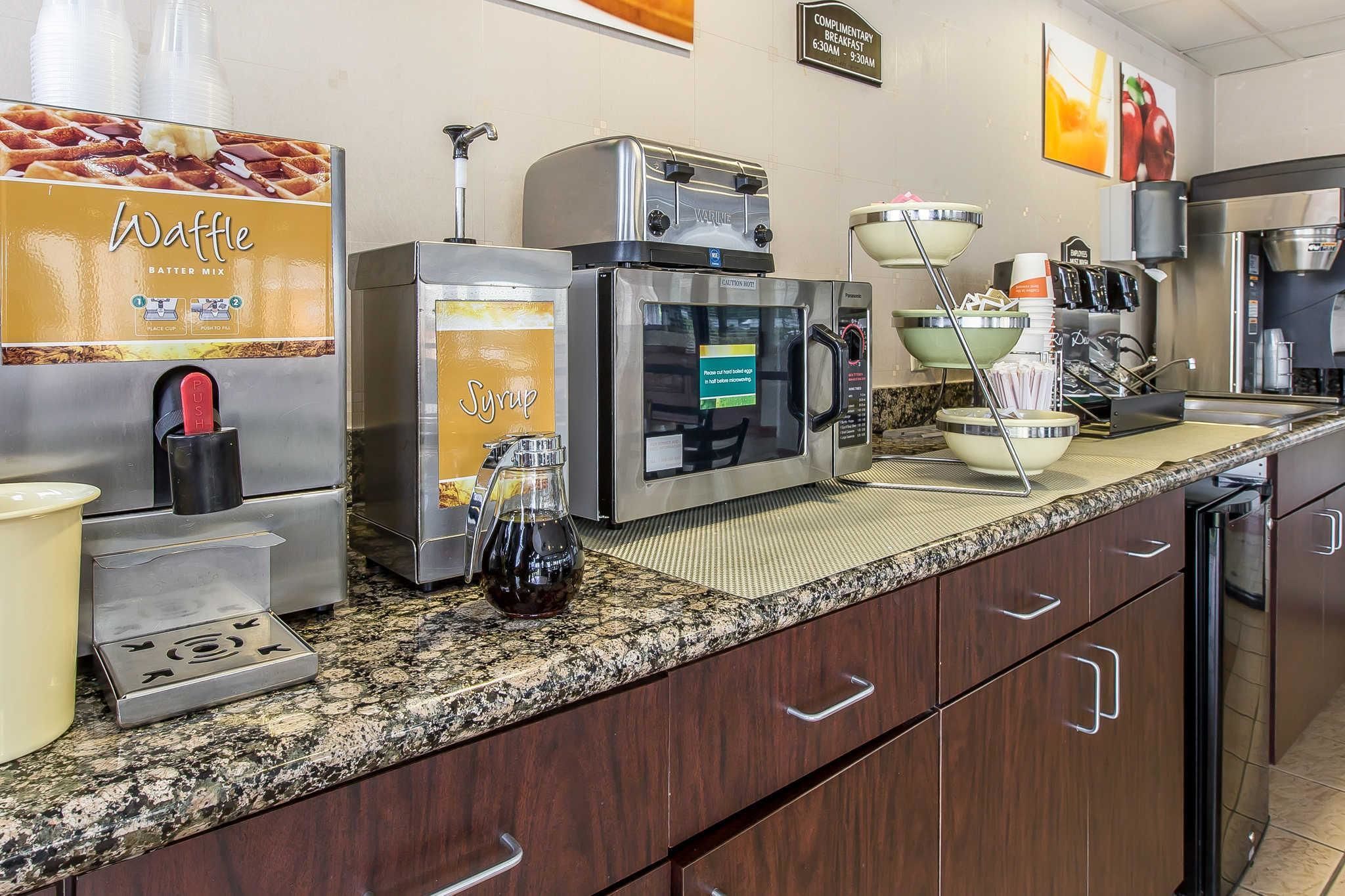 A commercial kitchen with waffle and syrup dispensers, a coffee machine, and a breakfast sign.