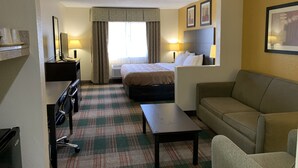 A hotel room with a bed, a desk, a chair, a sofa, and a small table. - Quality Inn Montgomery South (Montgomery)
