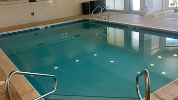 An indoor swimming pool with clear water, metal pool ladders, and a tiled wall with a 'NO DIVING' sign.