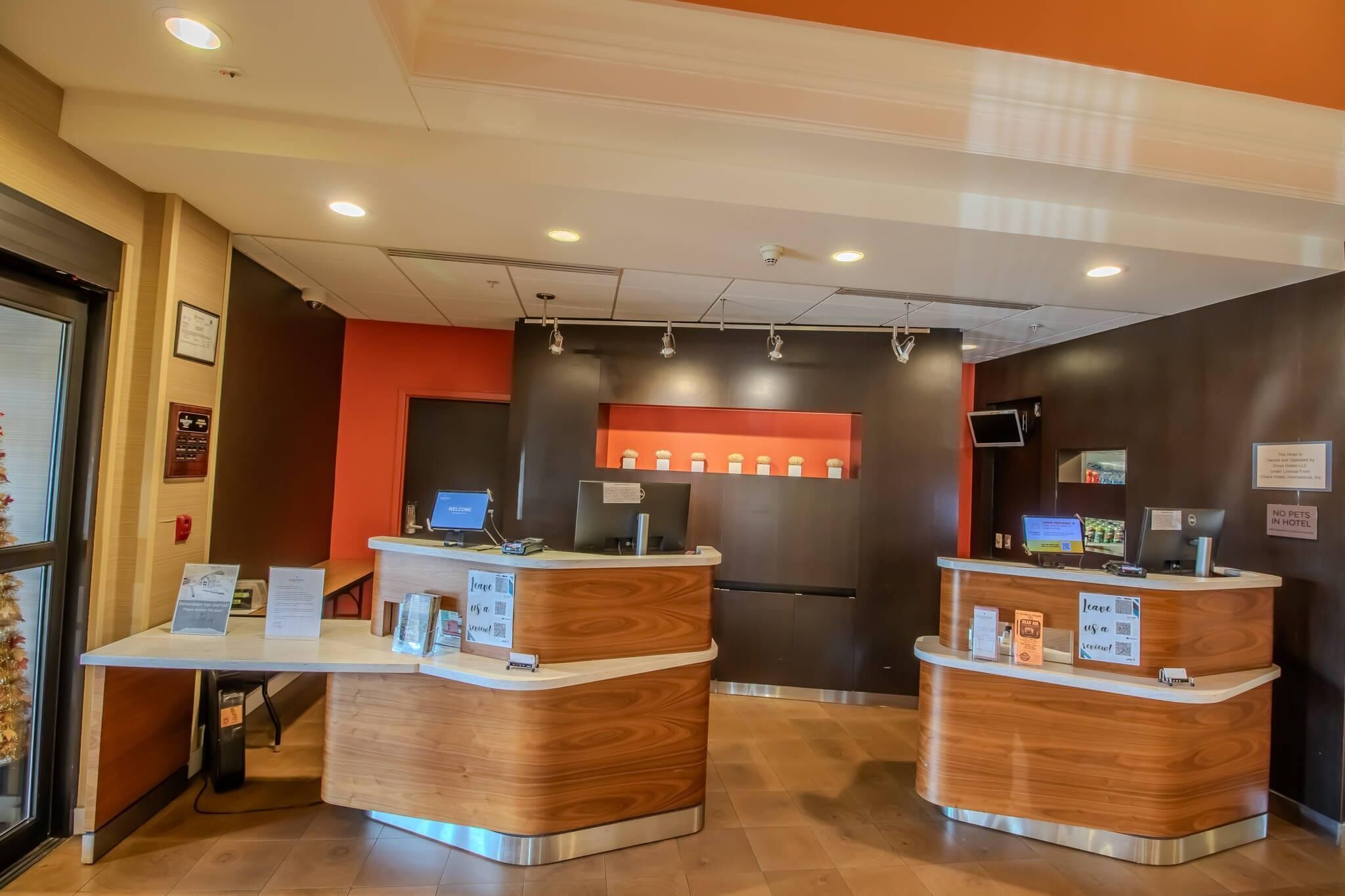 A reception desk with a wooden finish, a digital screen, and a sign indicating pet policy.