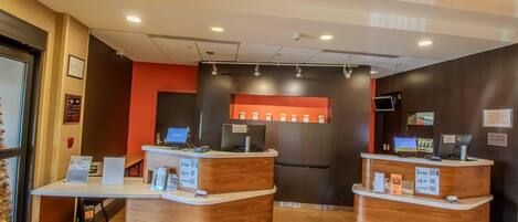 A reception desk with a wooden finish, a digital screen, and a sign indicating pet policy.